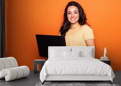 Smiling young blonde woman holding laptop posing isolated on yellow orange background. People lifestyle concept. Wall mural